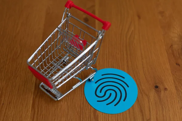 一辆购物车和一个木制桌子上有指纹的蓝色圆圈 网上购物的概念 — 图库照片