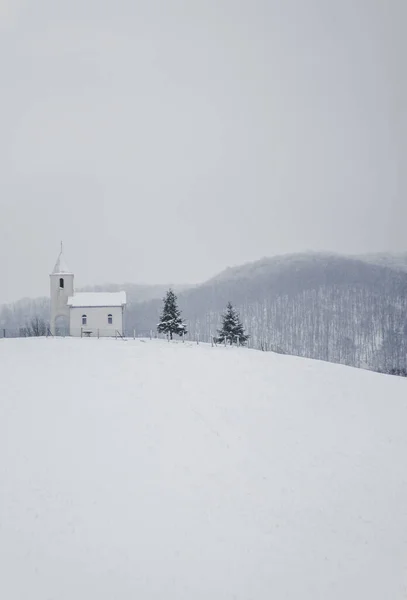 波斯尼亚和黑塞哥维那北部一座雪山顶上一座白色小教堂的垂直照片 — 图库照片