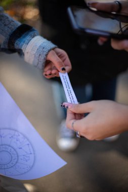 Rusça metni olan dar bir kağıt parçasını tutan kadınların dikey yakın çekimi. Seçili odak.