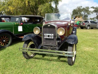 Eski kırmızı bordo Ford Model B 1932 kırsal alanda üstü açık dört kapı. Ön manzara. Doğa yeşili çimenler ve ağaçlar. Klasik araba şovu. Kopyalama alanı