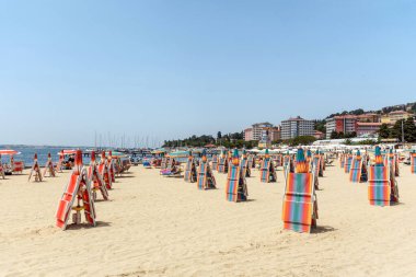 Mavi gökyüzüne karşı kumlu bir sahilde iskemle ve şemsiyeler. Portoroz, Slovenya.