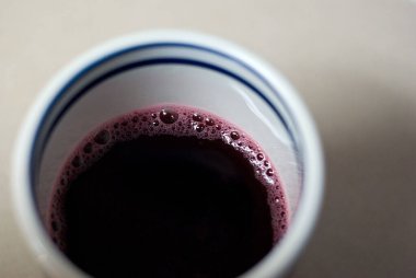 Beyaz bir masada bir bardak üzüm suyu manzarası.