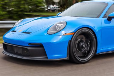 Modern mavi bir Porsche 911 GT3 spor arabası bulanık bir arka planda hareket ediyor