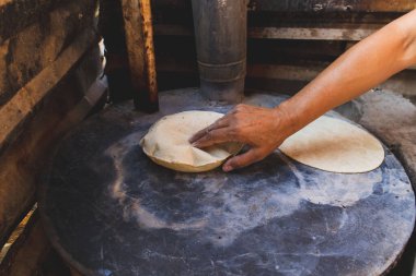 Meksikalı bir kadın, cuautla, jalisco, mex 'te ev yapımı tortilla yapmak için soba ve odun sobasında mısırlara işkence ediyor.