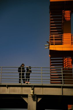 Koruyucu maskeli bir oğlu olan bir babanın binanın yanında dikey görüntüsü.