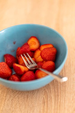 Masada bir kase taze dilimlenmiş çilek.
