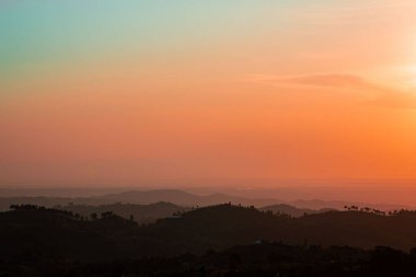 Büyüleyici bir günbatımı manzarası. Parlak güneş ve dağların üzerindeki bulutlar.