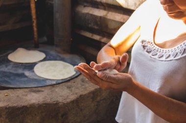Meksikalı bir kadın, cuautla, jalisco, mex 'te ev yapımı tortilla yapmak için soba ve odun sobasında mısırlara işkence ediyor.