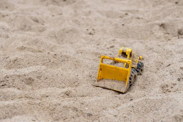Kumsaldaki bir kazıcı oyuncak kamyonunun yakın çekimi.