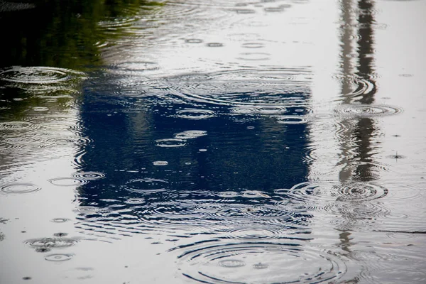 A closeup of a puddle on a road with the reflection of a sign on a rainy day