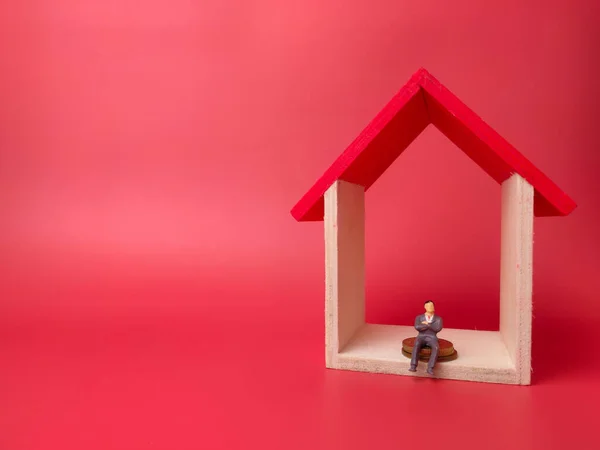 Kırmızı Arka Plandaki Ahşap Bir Evde Bozuk Paraların Üzerinde Oturan — Stok fotoğraf