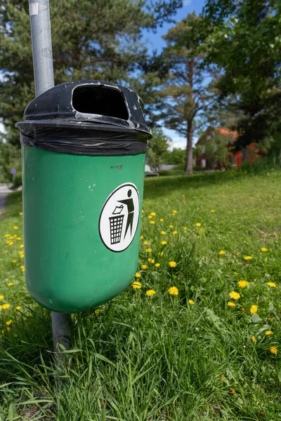 Bir direğe monte edilmiş yeşil bir çöp tenekesinin dikey görüntüsü.