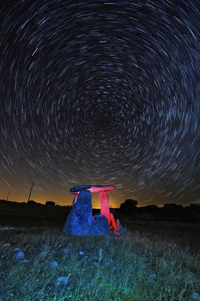 Hızlandırılmış yıldızların arka planına karşı megalithlerin dikey görüntüsü.