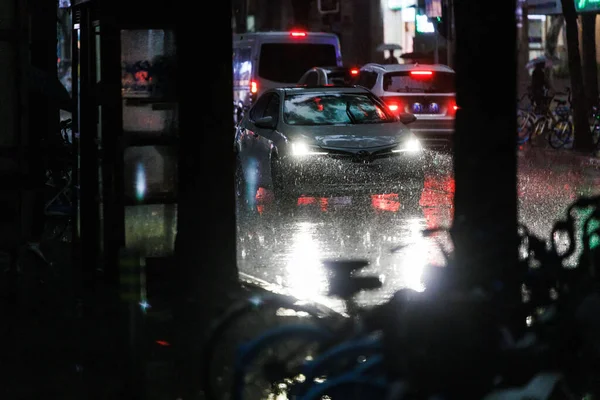 夜になると雨の降る通りで車のライトが落ちる — ストック写真