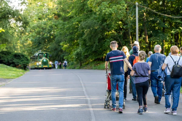 動物園のアスファルトの歩道を歩く人々のグループの背面ビュー — ストック写真