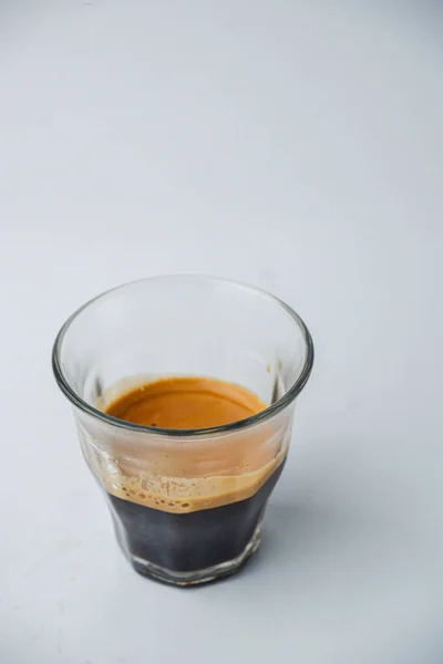白い背景に隔離されたエスプレッソコーヒーの透明なガラスカップの垂直ショット — ストック写真