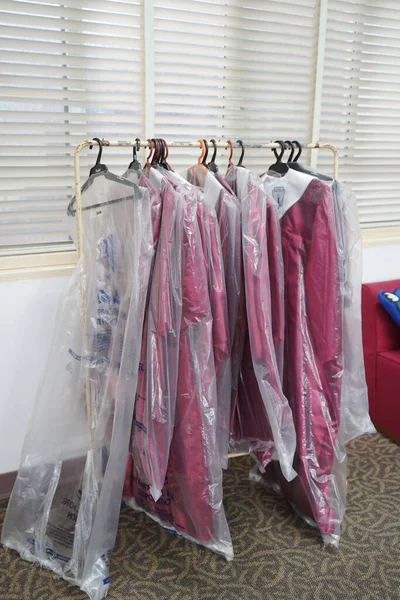 Pionowe Ujęcie Różowych Mundurów Plastikowej Osłonie Powieszone Szynie Odzieżowej Pokoju — Zdjęcie stockowe