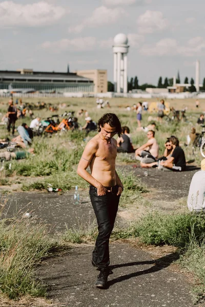 Arka planda Tempelhof Havaalanı olan üstsüz genç bir adamın sığ odak noktası.