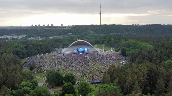 在一个露天音乐会上 一大群人在绿地里的一个大舞台上 周围环绕着树木 — 图库照片