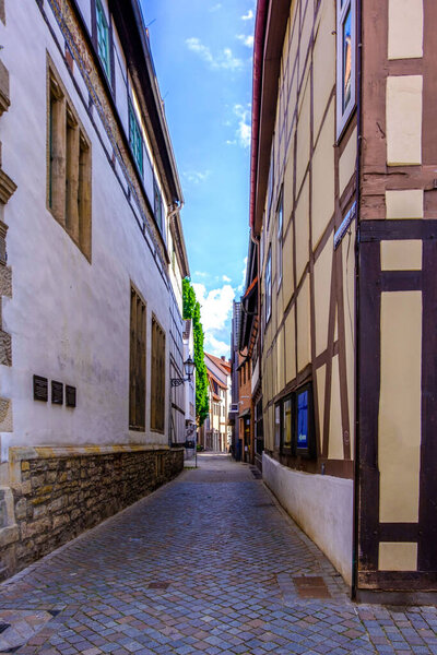 A vertical shot of a paved street between old-style buildings on a sunny day in Hamelin, Germany