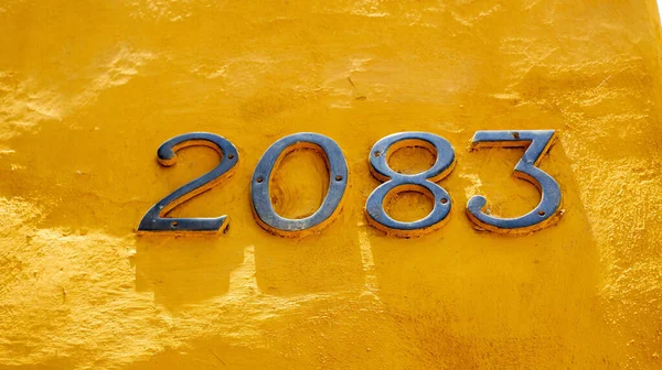 琥珀色黄墙背景图上2083金属编号的特写镜头 — 图库照片