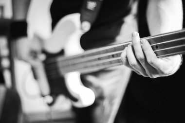 Elektro gitar çalan ellerin gri tonda yakın çekimi. Seçili odak.