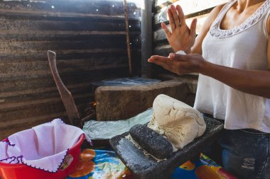 Meksikalı bir kadın, cuautla, jalisco, mex 'te ev yapımı tortilla yapmak için soba ve odun sobasında mısırlara işkence ediyor.