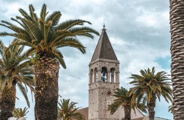 Trogir kilisesi bulutlu havada palmiye ağaçlarıyla çevrili..