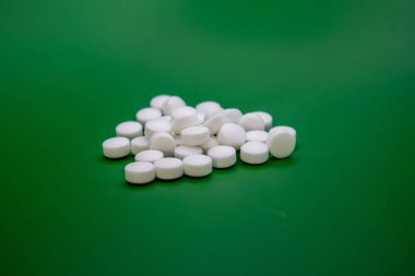 Yeşil arka planda beyaz hapların yakın plan çekimi..