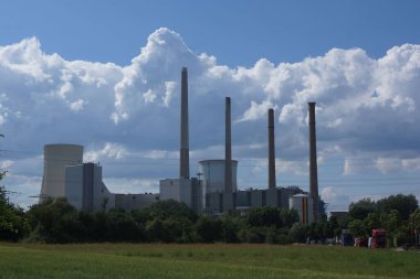 Almanya 'nın Hanau kenti yakınlarındaki Staudinger kömür yakıtlı enerji santrali, beyaz-mavi gökyüzüne karşı tarımsal bir arazide gömülü. Açık