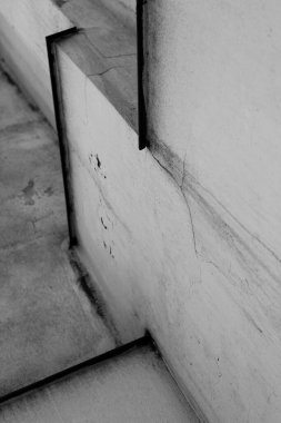 Metal detaylarla dolu pis bir duvarın dikey gri tonlu görüntüsü..