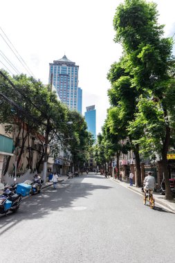 Şangay şehrinin arka planında modern binaların olduğu güzel bir cadde manzarası.