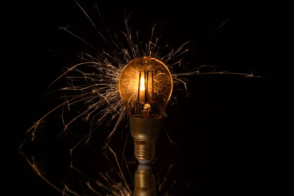 Lång Exponering Glödlampa Med Gnistor Reflekterande Yta Svart Bakgrund — Stockfoto