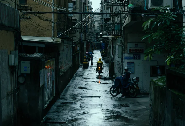 Красивый Снимок Людей Катающихся Велосипедах Узкой Улице Между Зданиями Дождливый — стоковое фото
