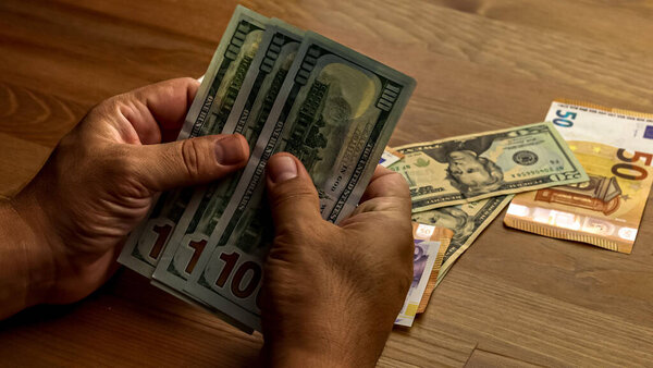Крупный план руки человека на деревянном столе с деньгами.