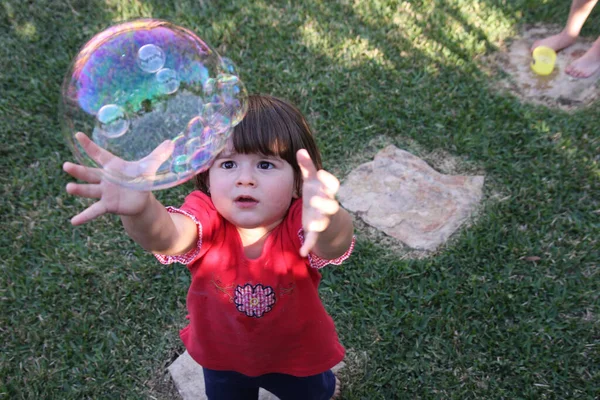 公園で泡を捕まえようとしてる少女のクローズアップ — ストック写真