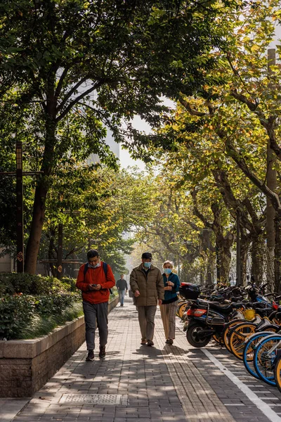 在中国上海 人们在公园的小径上与停放着的自行车和树木一起散步的纵向照片 — 图库照片