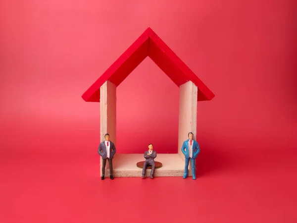 Kırmızı Arka Plandaki Ahşap Bir Evde Bozuk Paraların Üzerinde Oturan — Stok fotoğraf