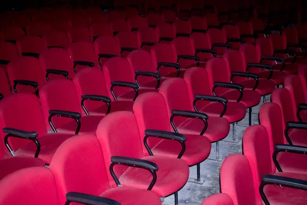 Some empty red chairs in a theater. Photo taken using flash light.