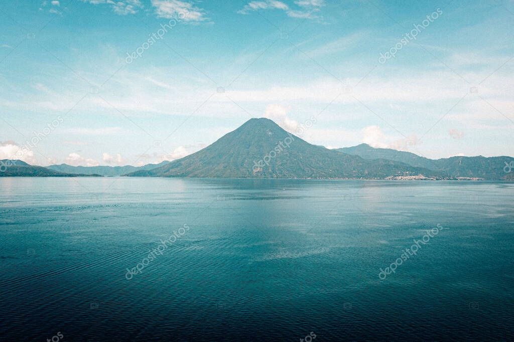 An aerial shot of the Lake Atitlan in the background of mountains on a cloudy day.