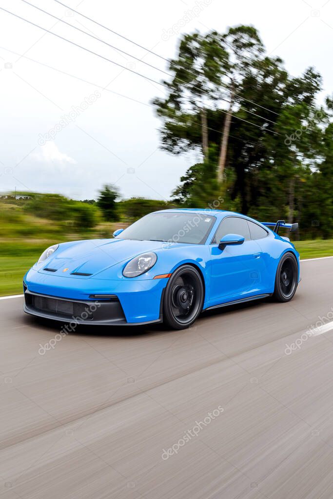 A vertical shot of a blue Porsche 911 GT3 sportscar in motion