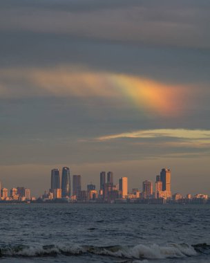 Gökyüzünde gökkuşağı olan bir kıyı şehri.