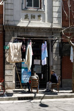 Yolun kenarında oturan ve Çin, Şangay 'da ürün satan kadınların dikey görüntüsü.