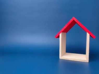 Mavi arka planda minyatür bir oyuncak evi, konut ve iş konsepti.