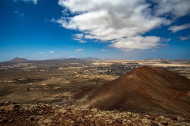 Fuerteventura volkanı, gündüz vakti mavi gökyüzünün altındaki bir kasabanın yakınında.