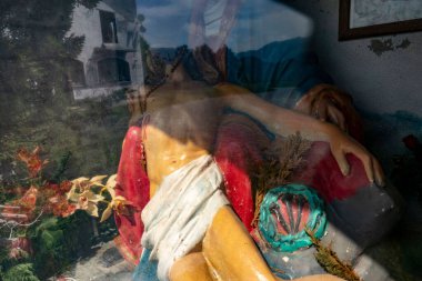 Pencerenin arkasındaki ölü İsa 'nın renkli bir heykeli.