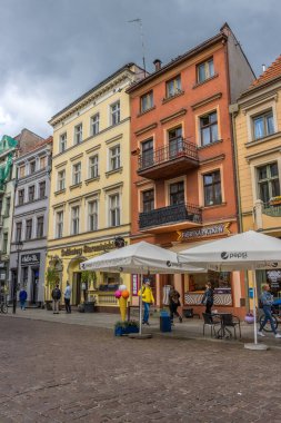 Polonya 'nın Torun kentindeki geleneksel binaların altında dükkanların önünde yürüyen insanların dikey görüntüsü