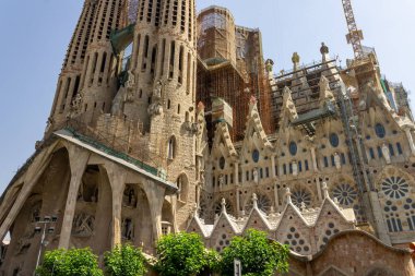 Sagrada Familia Bazilikası 'nın alçak açılı bir görüntüsü. Gökyüzünün altında yüksek kuleler ve kolonlar var.