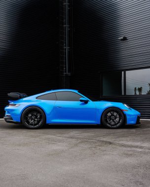 Modern mavi bir Porsche 911 GT3 spor arabasının dikey yan görüntüsü.