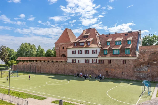 ポーランドのトルンを背景に建物のある緑のサッカー場の人々のグループ — ストック写真